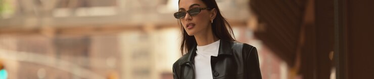 Model is wearing a black faux leather jacket over a white tank top.