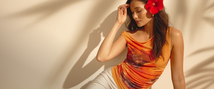 Model is wearing an orange single shoulder mesh mini dress with a floral print.