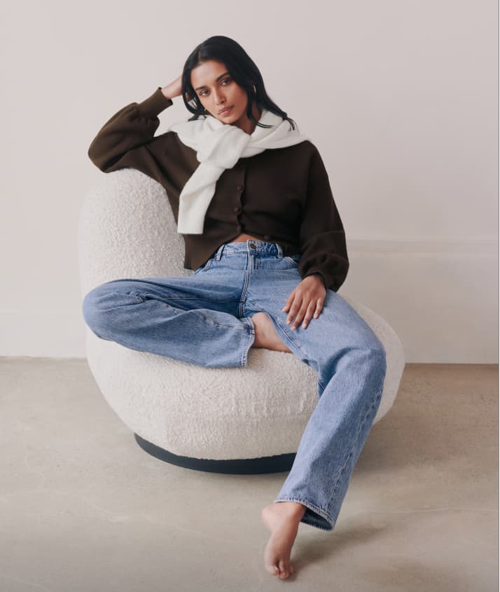 La mannequin porte un cardigan brun et un jean bleu pâle.