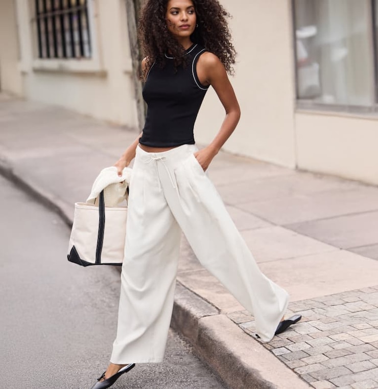 Model is wearing a black tank top with white wide leg pants.