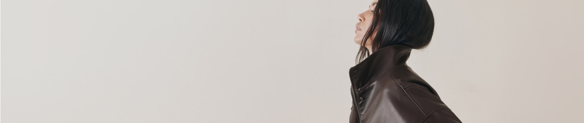 Model is wearing a brown faux leather bomber jacket.