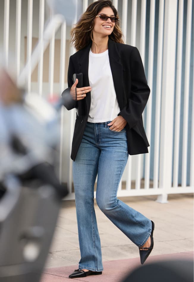 Model is wearing a relaxed black blazer over a white T-shirts and light indigo jeans.