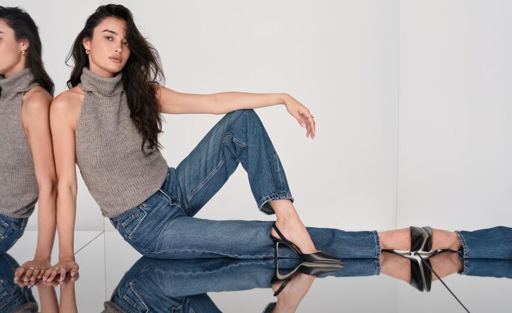 Model is wearing a brown knit halter top and blue wide leg jeans.