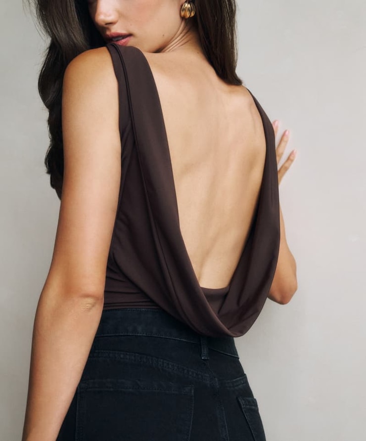 Model is wearing a brown cowl back bodysuit and black jeans.