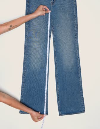 Placez le ruban à mesurer de la couture de la fourche à l'ourlet d'une paire de jeans.