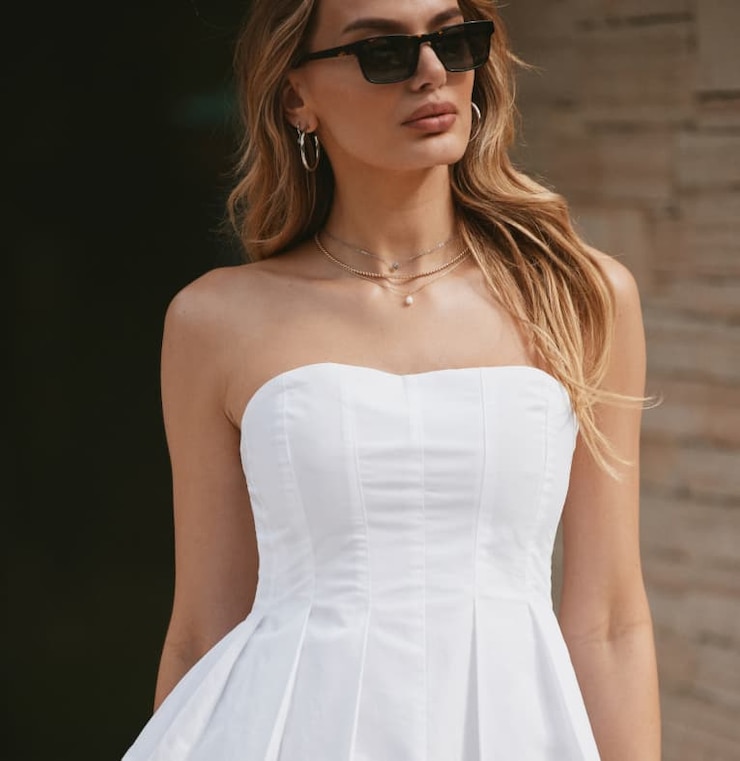 Model is wearing a white peplum poplin tube top.