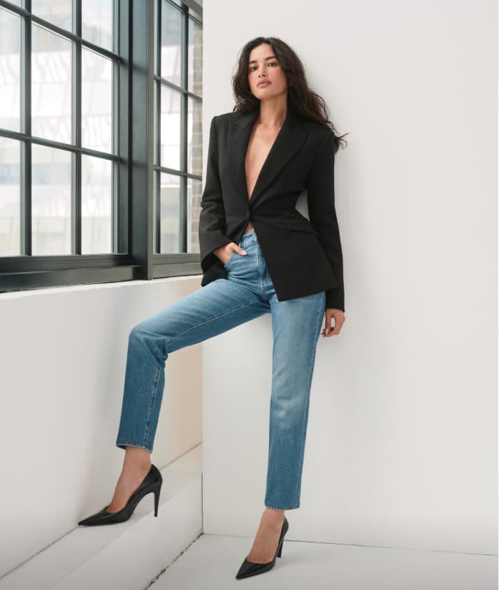  Model is wearing a black cinched cardigan and medium wash slim leg jeans.