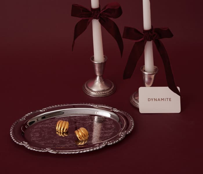 Two white tapered candles next to earrings on a silver platter.