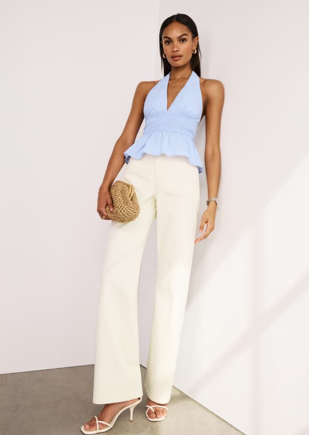 Model is wearing a blue peplum poplin halter top and off white jeans.
